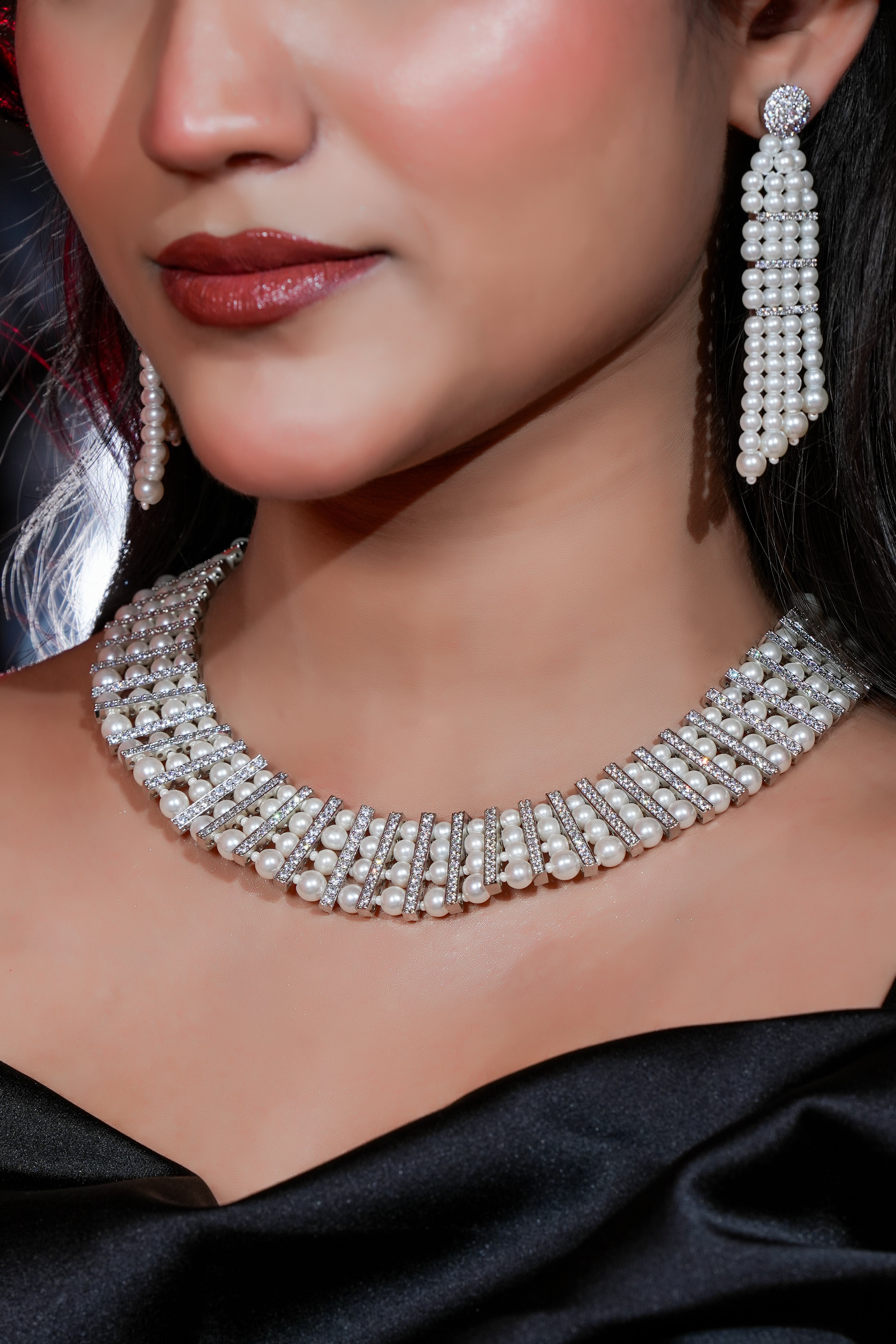 Close-up of a woman wearing a sparkling necklace and earrings on a black background
