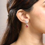 Close-up of a woman wearing a red teardrop earring with a silver setting.