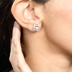 Close-up of a person wearing a diamond earring with a hand touching the earlobe.